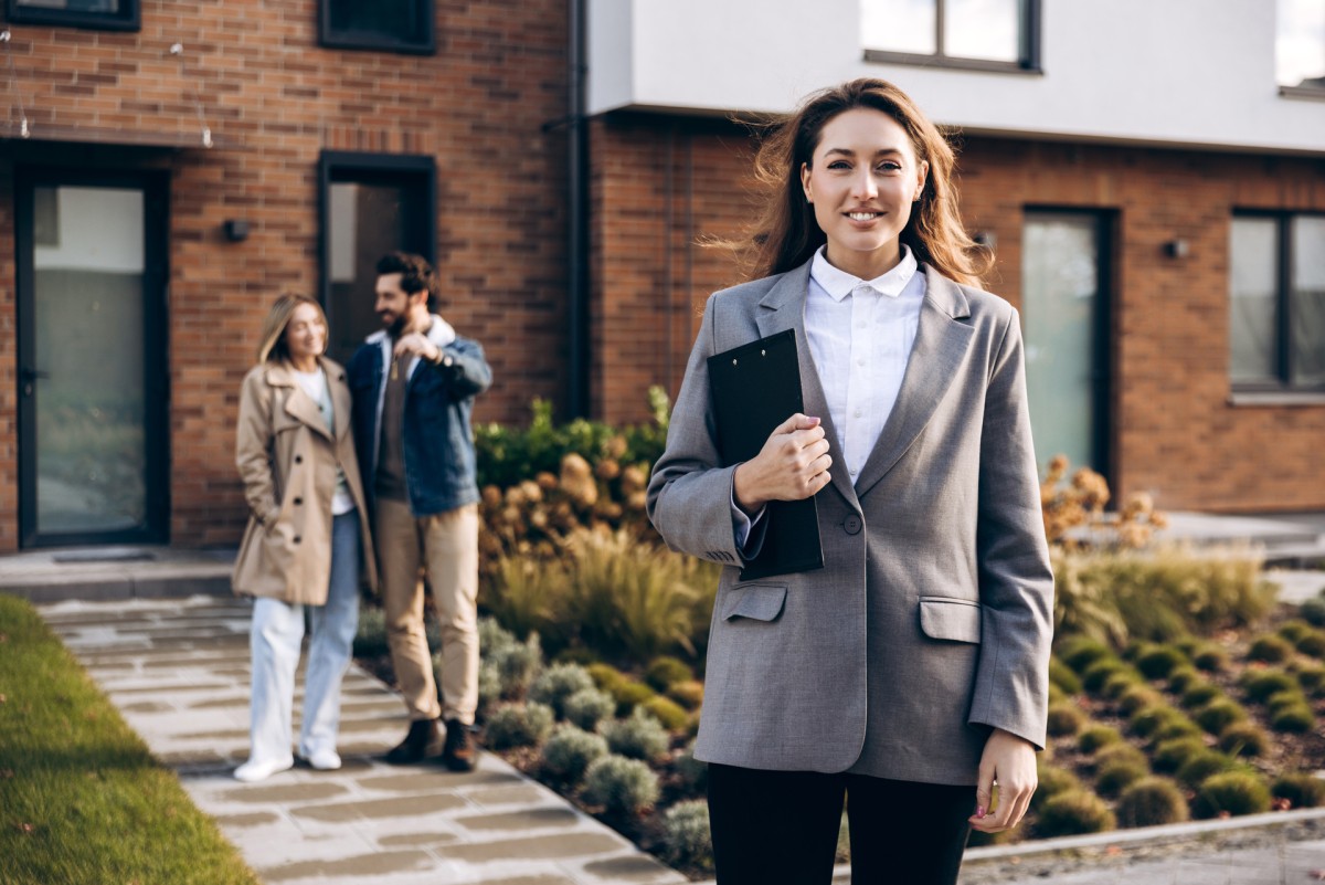 Real estate agent with new homeowners outside house