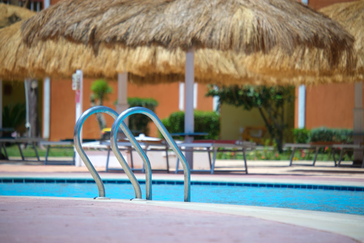Resort pool with straw umbrellas and lounge chairs