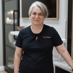 Woman in black shirt standing indoors.