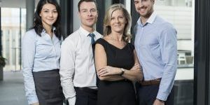 Four professionals in office environment posing together.